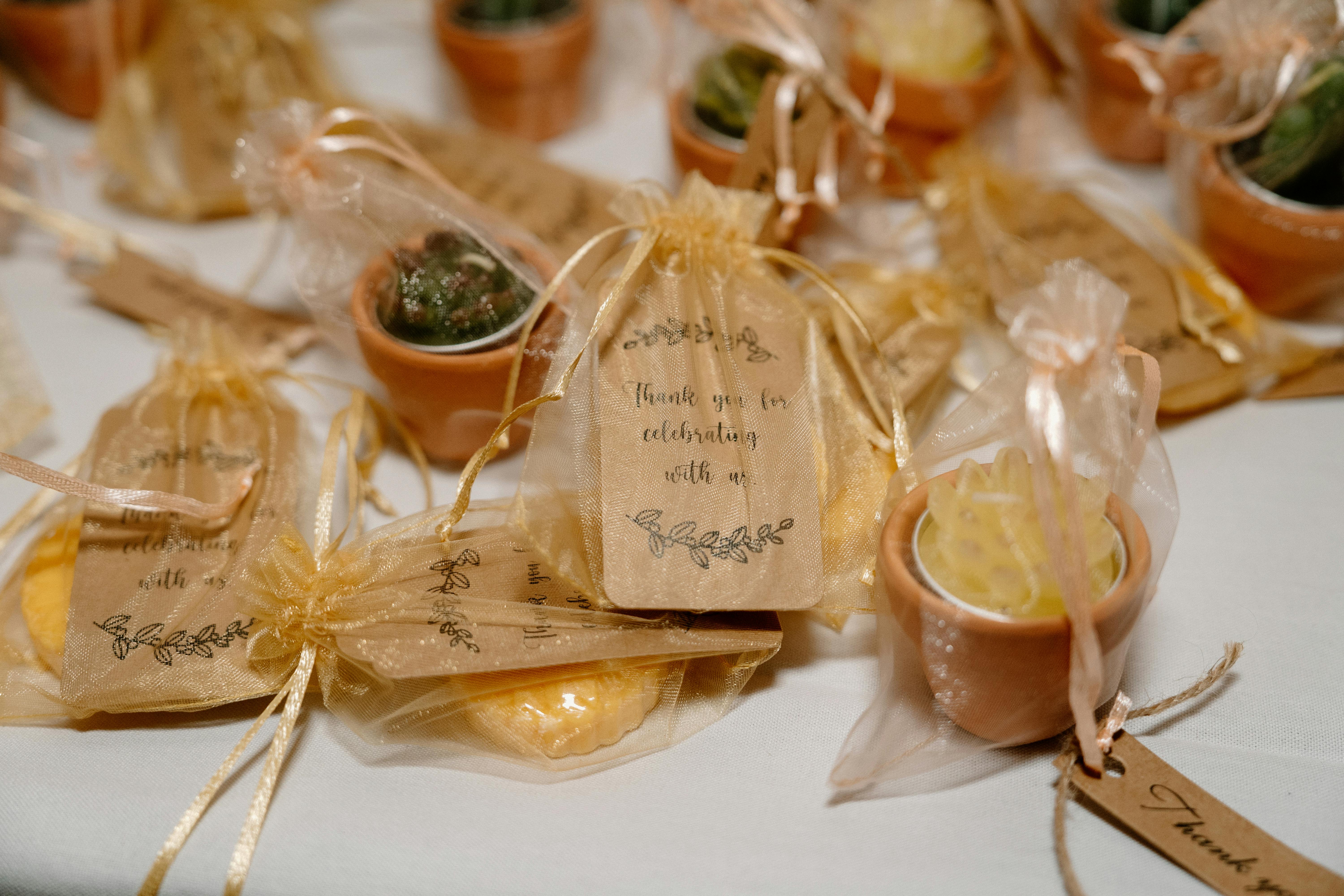 Wedding favors wrapped in organza bags with notes that say "Thank you for celebrating with us"