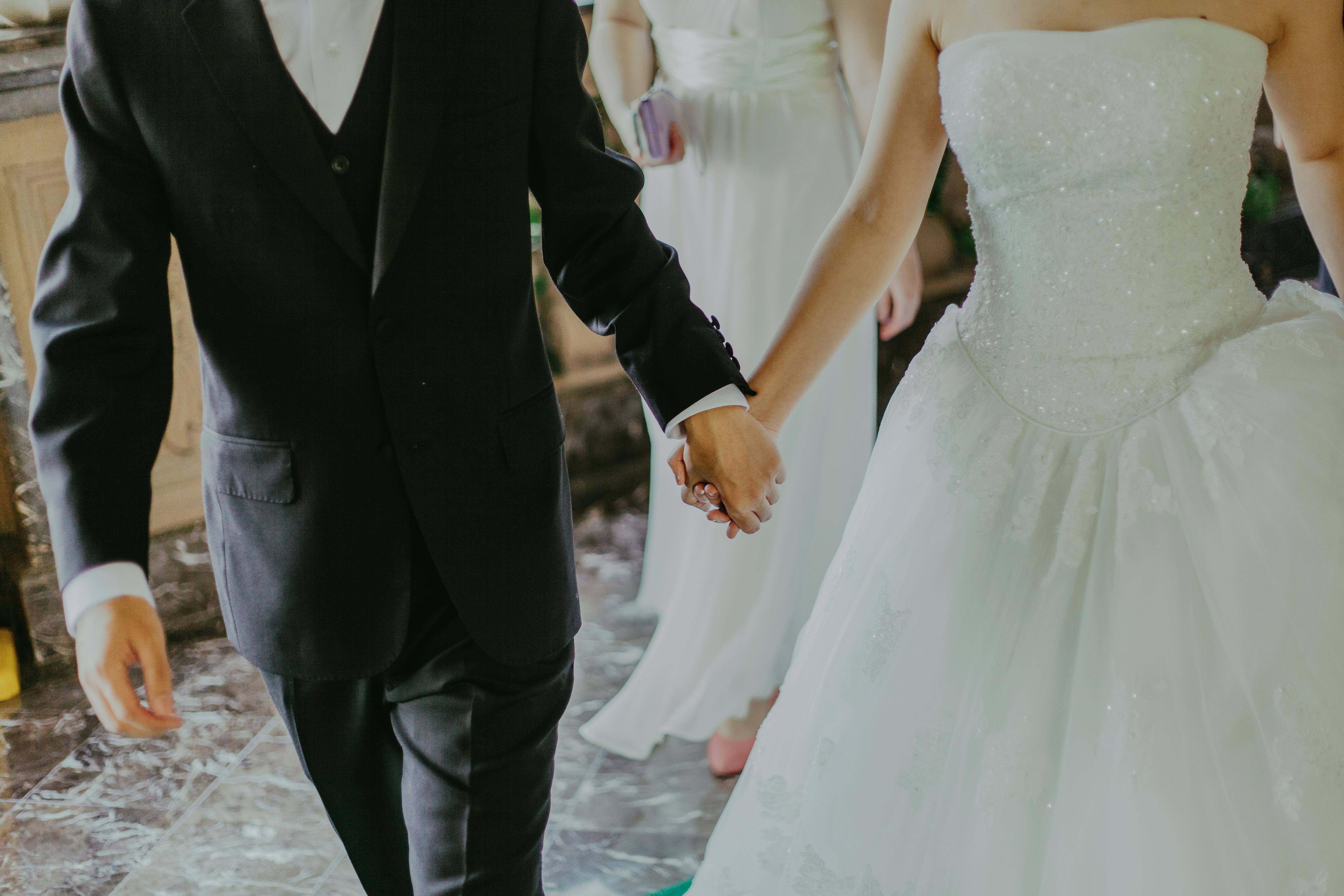 A bride and groom hold hands.