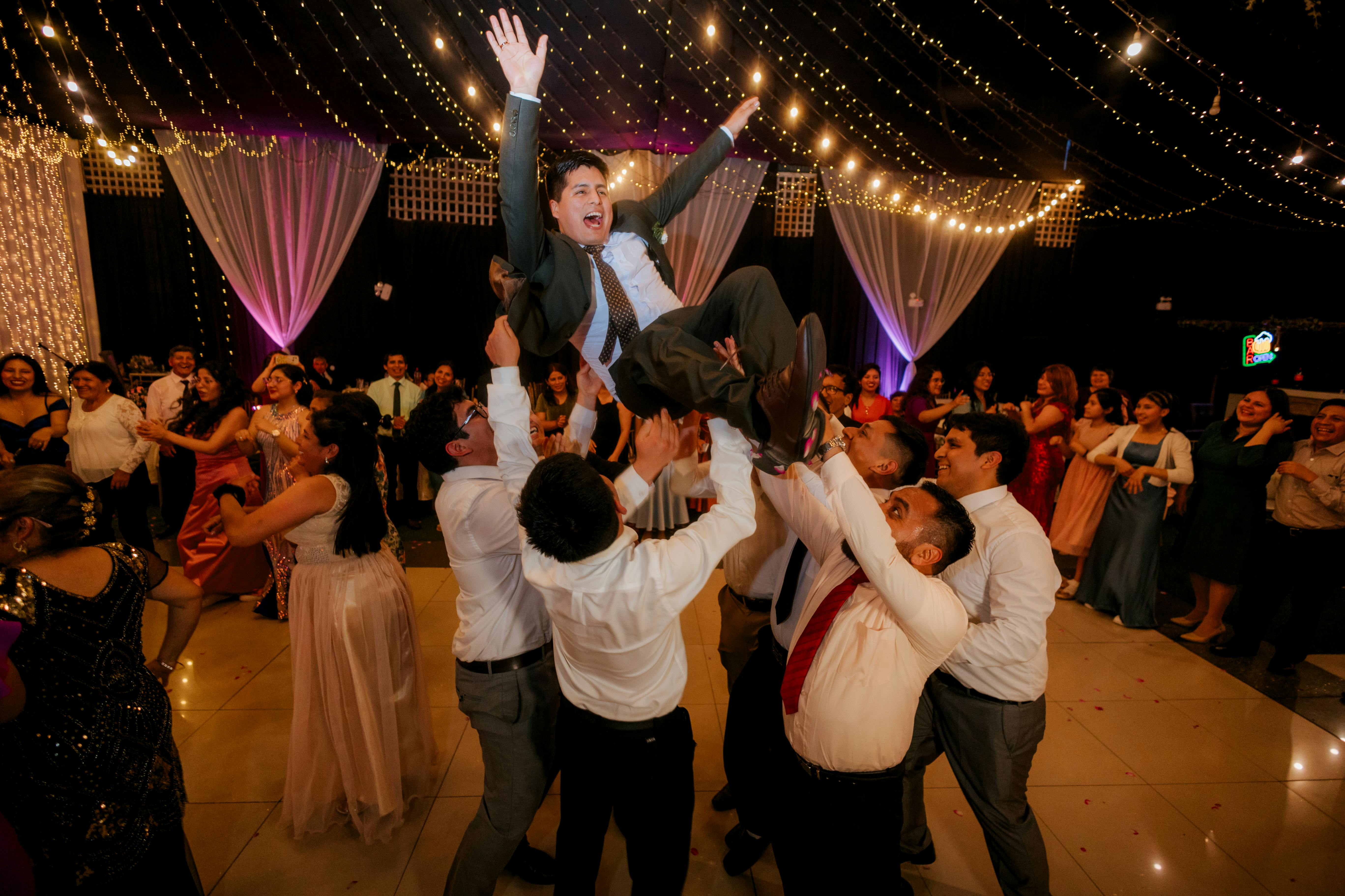 A man is thrown in the air by his friends during his wedding reception.