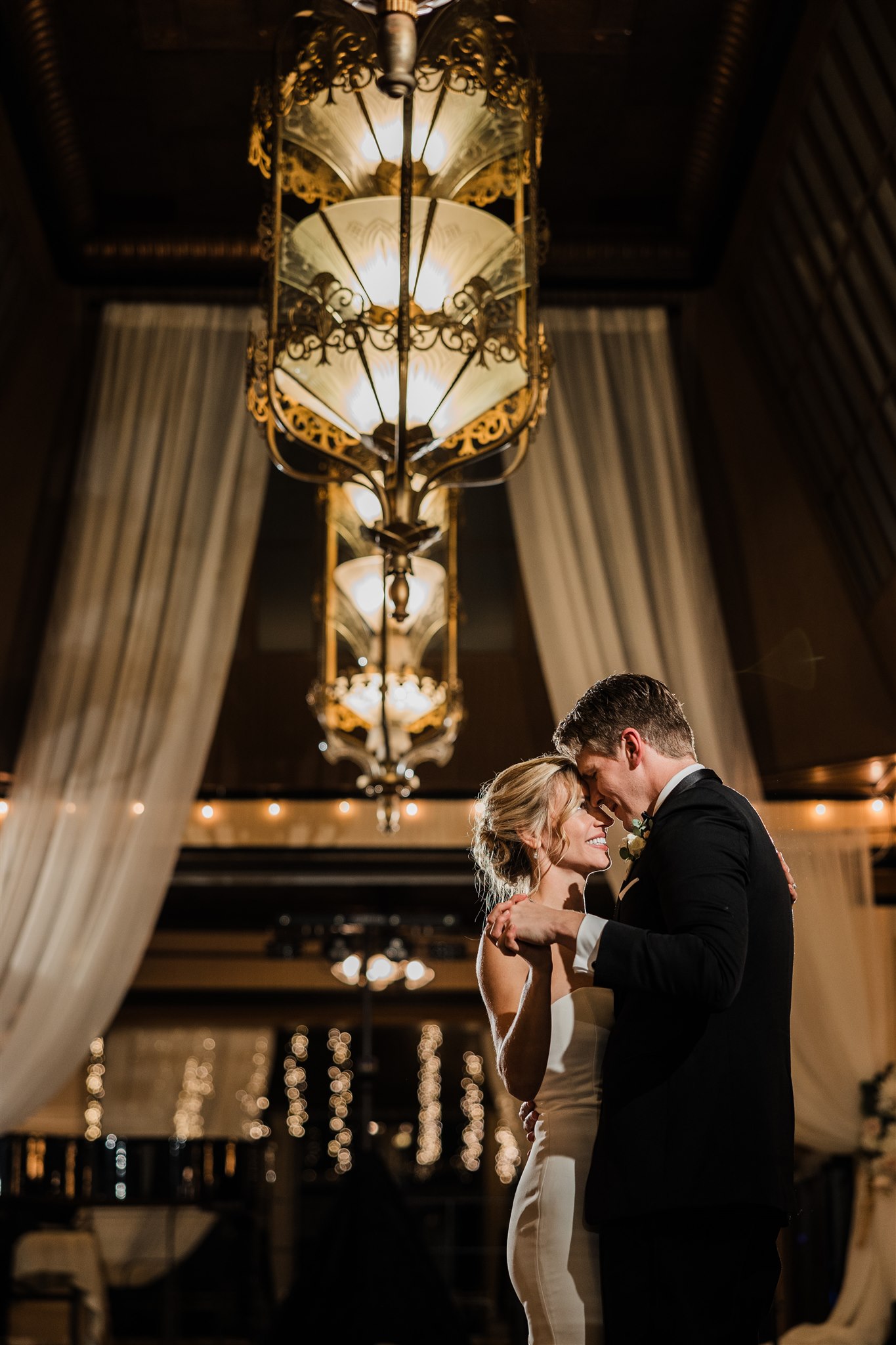A bride and groom share a dance under the chandeliers at Imperia at Lake Union