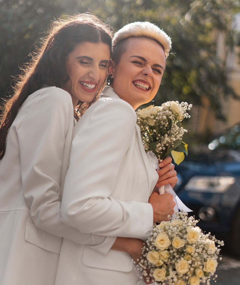 two brides smiling with handfuls of flowers